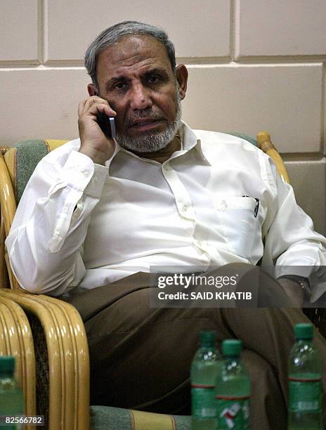 Palestinian senior Hamas official Mahmud Zahar talks on the phone as he waits at the Rafah border terminal crossing between the southern Gaza Strip...