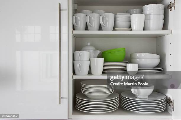 white crockery stacked in cupboard with green bowl - cabinet stock pictures, royalty-free photos & images