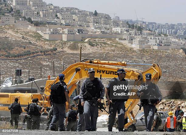 Israeli policemen walk near an Israeli army bulldozer as it demolishes a Palestinian house that was built without municipality permission in the...