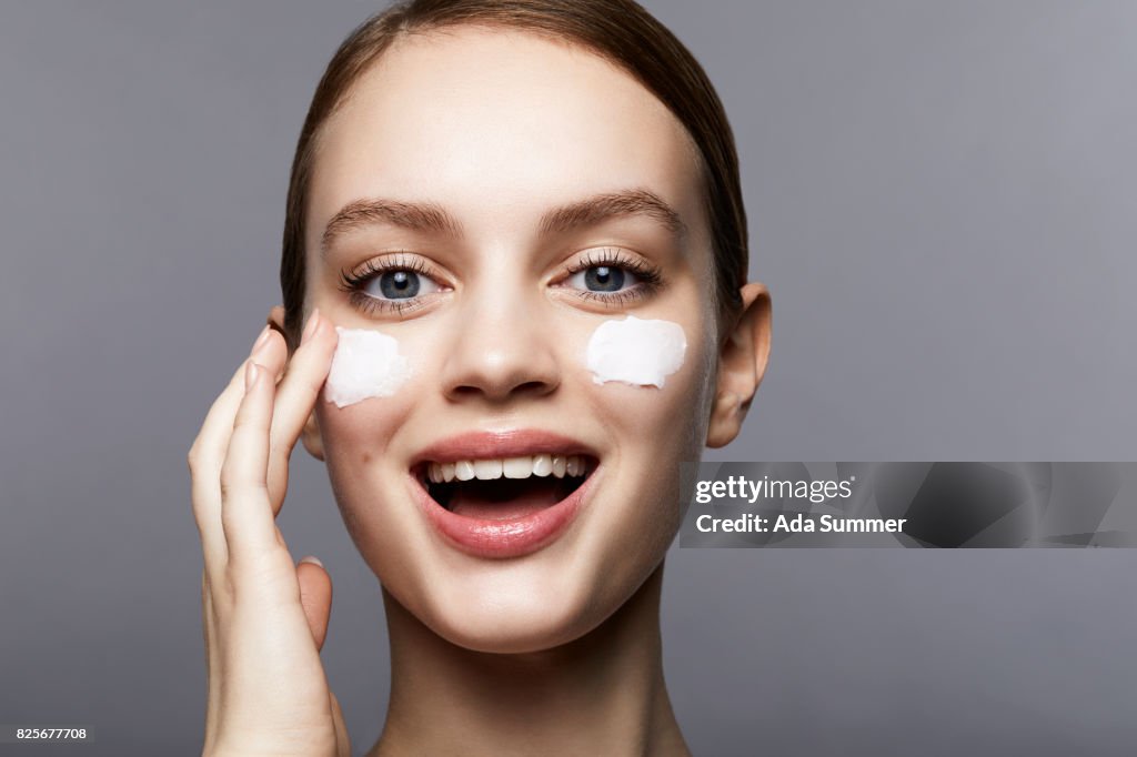 Woman with streaks of lotion on face