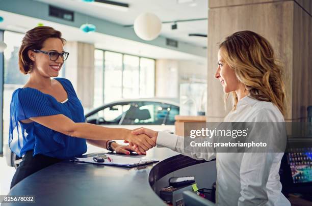 concesionario de automóviles está sacudiendo la mano con un cliente después de éxito - encogido fotografías e imágenes de stock