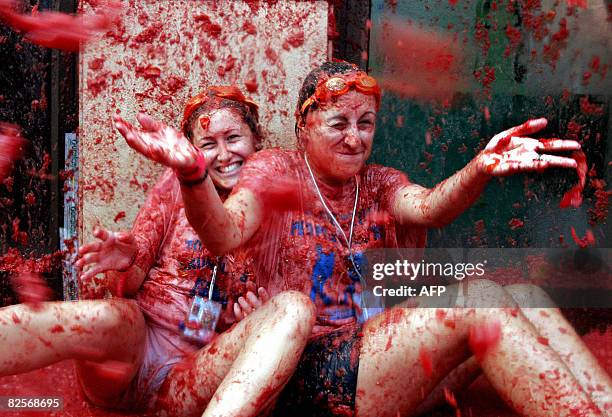 Women covered in tomato juice smile during the "Tomatina", a traditional festival where people throw tomatoes at each other, on August 27, 2008 in...