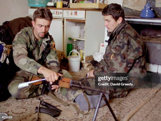 Field commander Metat, left, cleans his Kalashnikov AK-47 rifle, while a 17 year-old soldier looks on February 24, 2001 in the village of Bukovac,...