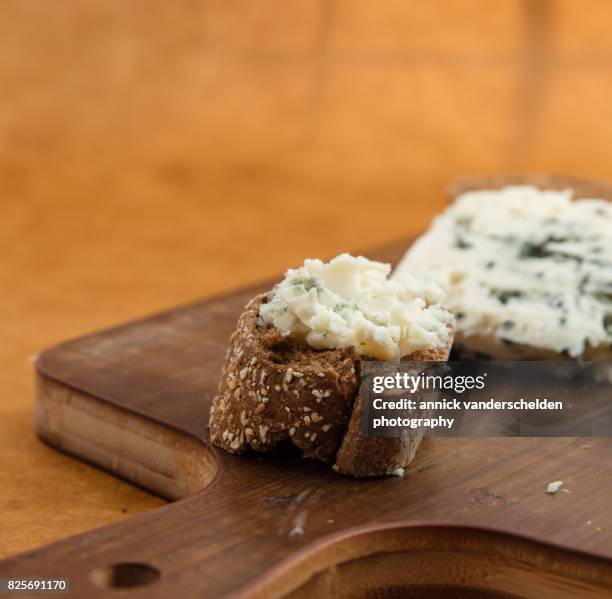 spread roquefort cheese on cut baguette piece. - roquefort stock pictures, royalty-free photos & images