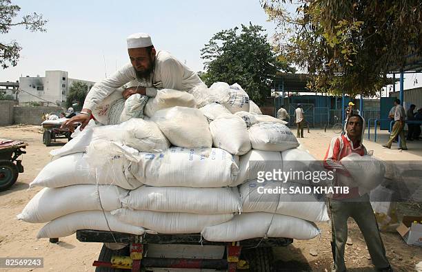 Palestinian man loads a cart with flour sacs donated by the United Nations Relief and Works Agency for Palestine Refugees on July 13, 2008 in Rafah,...
