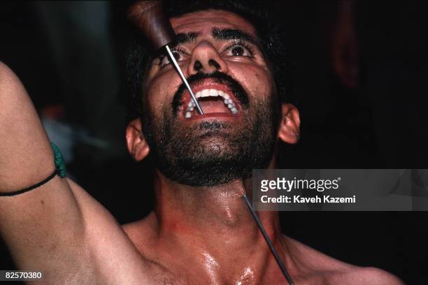 Kasnazani dervish pierces his lower jaw and throat with a skewer whilst in trance, during a remembrance ceremony in Sanandaj , capital of the...