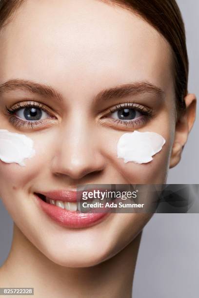 woman with streaks of lotion on face - beauty studio moisturisers stock-fotos und bilder