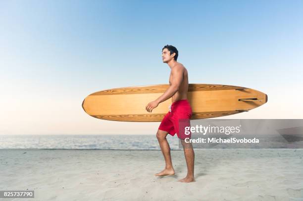 hispanic surfer walking - board shorts stock pictures, royalty-free photos & images