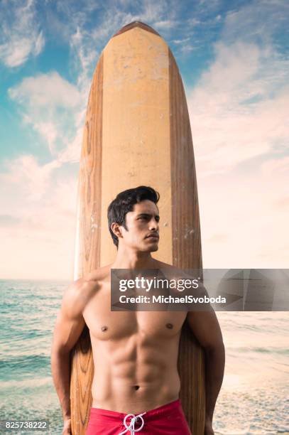 hispanic surfer with a dramatic sunset at the ocean - board shorts stock pictures, royalty-free photos & images