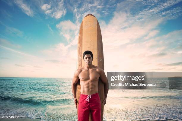 hispanic surfer with a dramatic sunset at the ocean - board shorts stock pictures, royalty-free photos & images