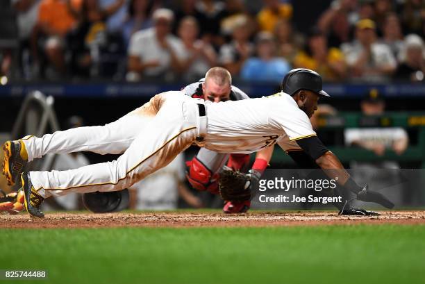 Starling Marte of the Pittsburgh Pirates dives back to home plate in front of Tucker Barnhart of the Cincinnati Reds during the sixth inning against...