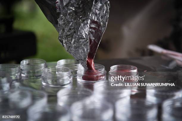 This photo taken on July 24, 2017 shows melted lipstick being poured into small plastic containers to be given to current female inmates in Bangkok....