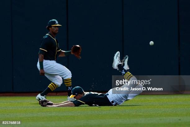 Jaycob Brugman of the Oakland Athletics dives for but is unable to field a fly ball hit for a double by Brandon Crawford of the San Francisco Giants...