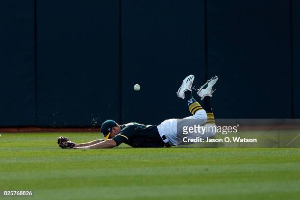 Jaycob Brugman of the Oakland Athletics dives for but is unable to field a fly ball hit for a double by Brandon Crawford of the San Francisco Giants...