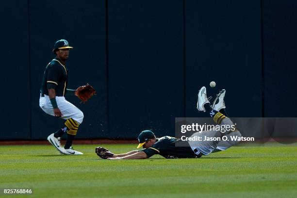 Jaycob Brugman of the Oakland Athletics dives for but is unable to field a fly ball hit for a double by Brandon Crawford of the San Francisco Giants...