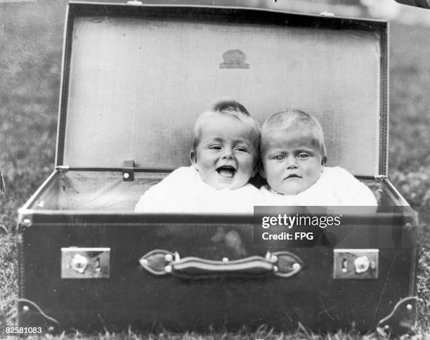 Two babies packed into a large suitcase, circa 1930.