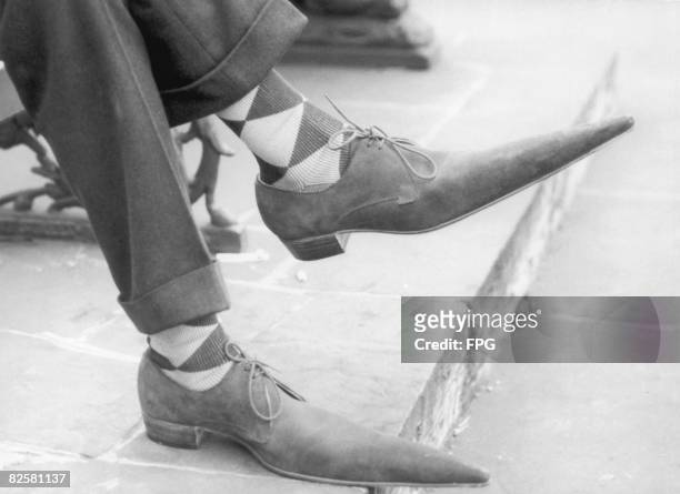 Pair of feet clad in lace-up shoes with long pointy toes, 1960.