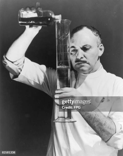 Scientist pouring liquid into a graduated cylinder, circa 1950.