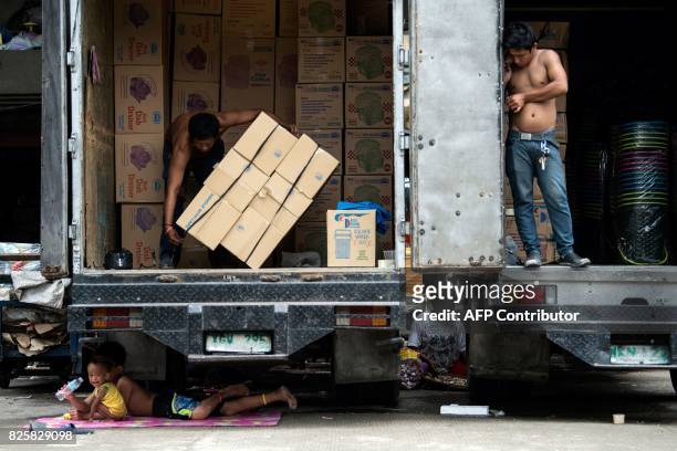 Children rest under a truck in Manila on August 3, 2017. / AFP PHOTO / Noel CELIS