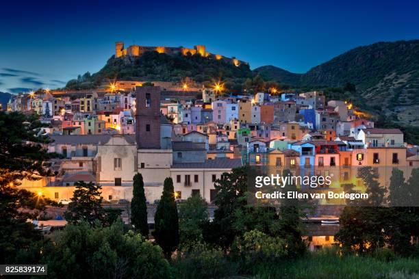 nighttime view over the colourful town of bosa and its medieval castle along the temo river - sardinien stock-fotos und bilder