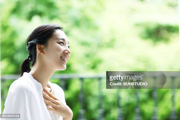 woman resting on a balcony - 胸に手を当てる ストックフォトと画像