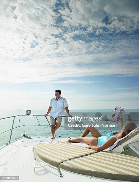 woman reading magzine while man relaxes on boat. - magazine retreat day 2 stock pictures, royalty-free photos & images