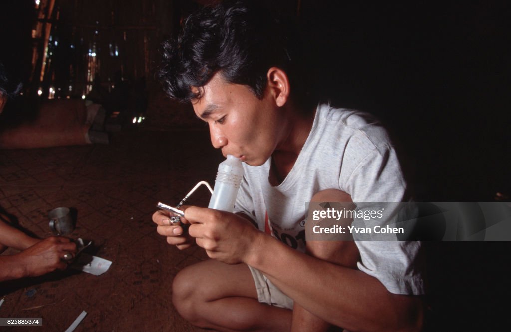 A hill tribe youth uses a converted plastic bottle to inhale...