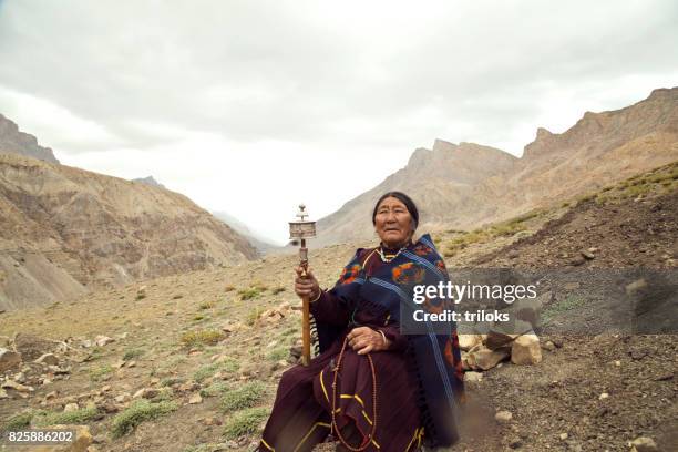 old woman holding hand prayer wheel - traditional clothing stock pictures, royalty-free photos & images