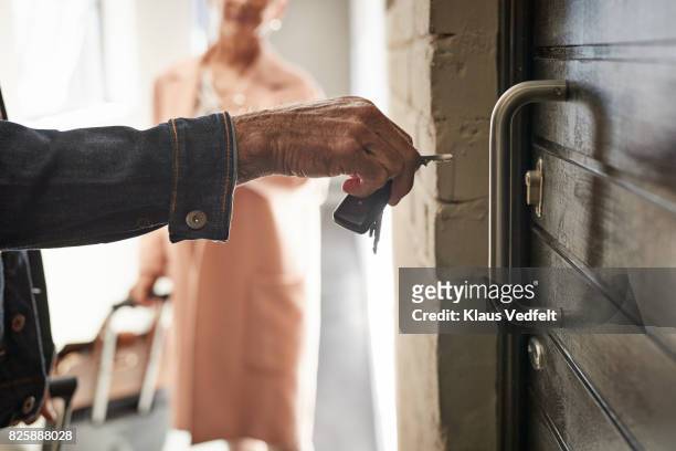 close-up of mature couple opening door to holiday rental apartment with key - close up of couple opening door to apartment with key stock-fotos und bilder