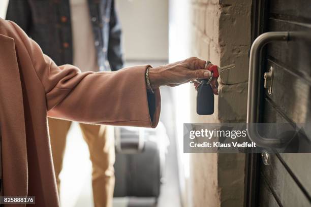 close-up of mature couple opening door to holiday rental apartment with key - close up of couple opening door to apartment with key fotografías e imágenes de stock