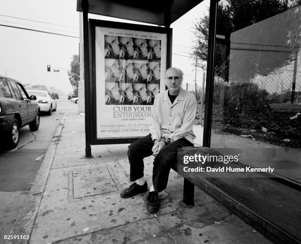 Curb Your Enthusiasm star and creator Larry David sits at the bus stop in front of his poster on October 20, 2000 in Los Angeles, California.