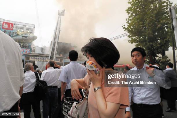 Woman covers her face with towel walks past the fire site outside Tokyo's famed Tsukiji fish market on August 3, 2017 in Tokyo, Japan. The blaze in...