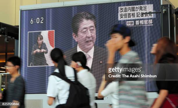 People walk past a giant screen broadcasting the news of Prime Minister Shinzo Abe reshuffling his cabinet on August 3, 2017 in Osaka, Japan. Prime...