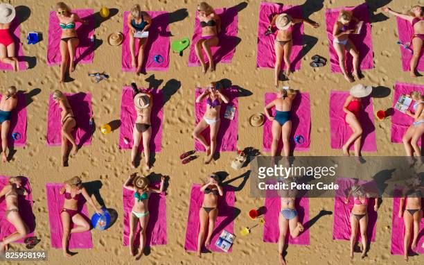 aerial shot of duplicated woman sunbathing on beach - multiple images of the same woman stock pictures, royalty-free photos & images