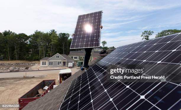 Jack Doherty, photovoltaic project manager for Revision Energy, installs a solar panel on a home at OceanView at Falmouth. The company, which employs...