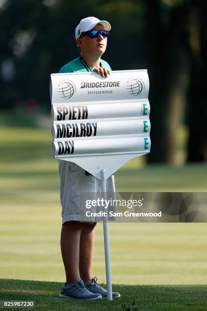Standard bearer holds a scoreboard featuring the group of Jordan Spieth, Rory McIlroy of Northern Ireland and Jason Day of Australia during thei...