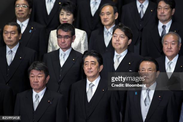 Shinzo Abe, Japan's prime minister, front row center, poses for a group photograph with his new cabinet members at the Prime Minister's official...