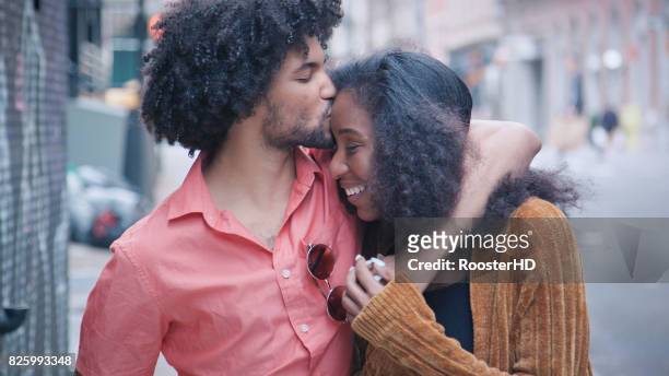 attraktives afroamerikanischen paar spaziergang und kuss auf urban street - afro amerikanische kultur stock-fotos und bilder