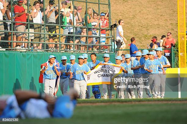 The Waipio Little League team runs with the state flag of Hawaii after winning the World Series Championship game against the Matamoros Little League...