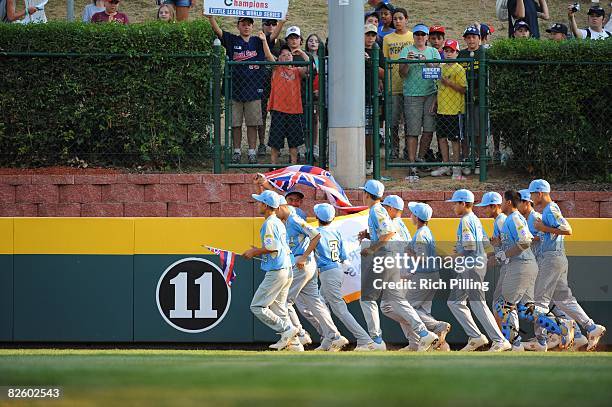 The Waipio Little League team runs with the state flag of Hawaii after winning the World Series Championship game against the Matamoros Little League...