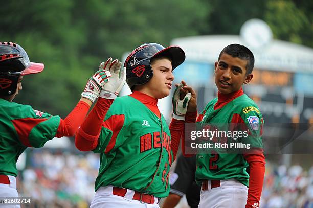 Jesus Sauceda of the Matamoros Team is greeted by Octavio Salinas and Tomas Castillo after hitting a home run during the World Series Championship...