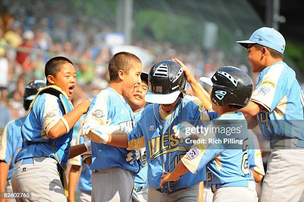 Tanner Tokunaga of the Waipio Little League team is greeted by teammates after hitting a home run during the World Series Championship game against...
