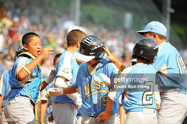 Tanner Tokunaga of the Waipio Little League team is greeted by teammates after hitting a home run during the World Series Championship game against...