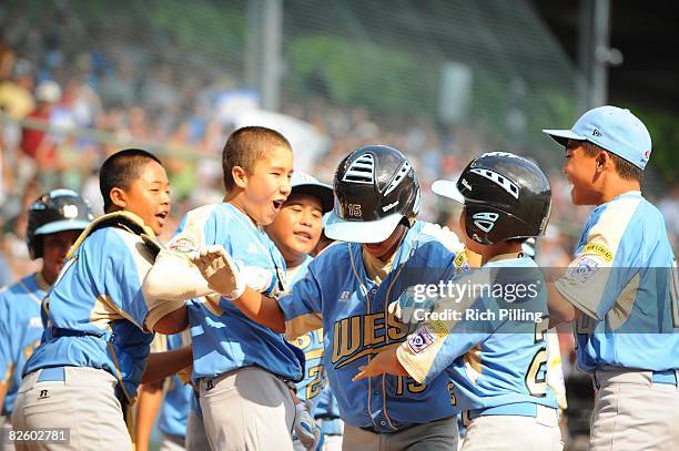 Tanner Tokunaga of the Waipio Little League team is greeted by teammates after hitting a home run during the World Series Championship game against...