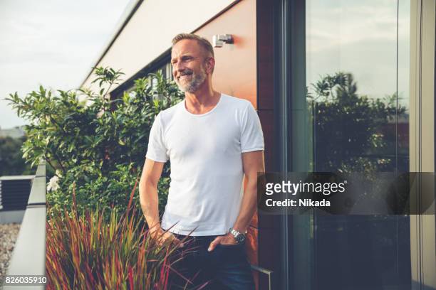 handsome man standing on a balcony - mature men imagens e fotografias de stock