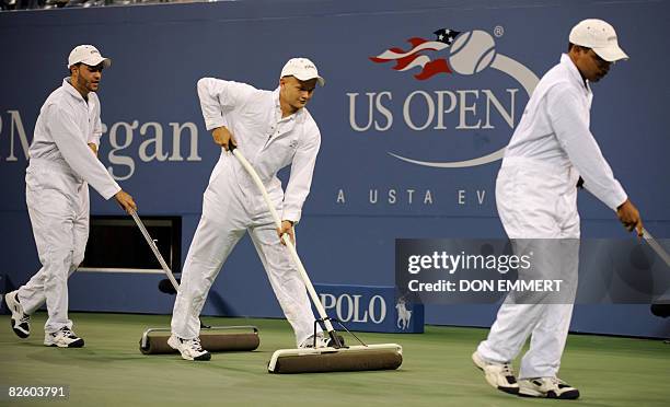 Workers dry the court during a match between Lindsay Davenport of the US and Marion Bartoli of France at the US Open tennis tournament August 29,...