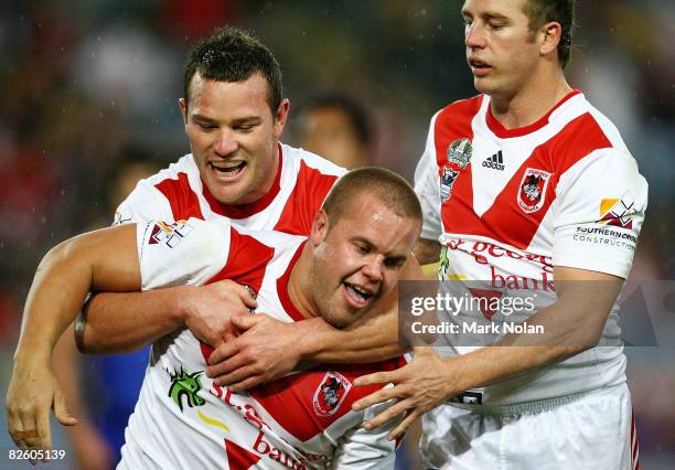 Dan Hunt of the Dragons is congratulated by team mates Dean Young and Stuart Webb after he scored during the round 25 NRL match between the St...