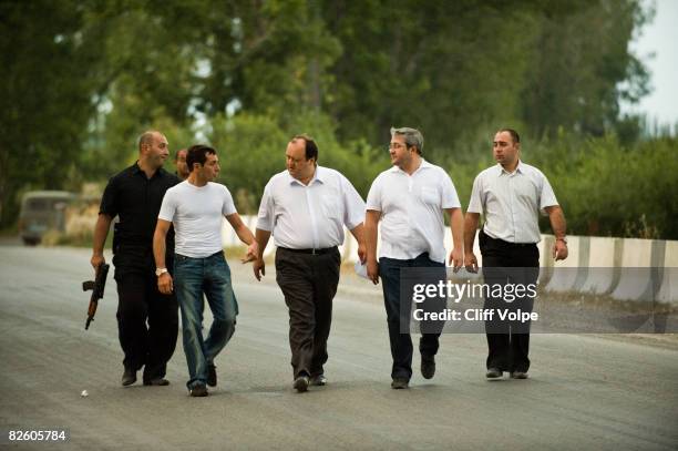 Georgian security forces and politicians walk back towards their cars after handing over three captured Ossetian militia members at the Russian...