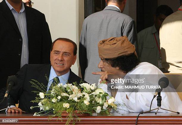 Libyan leader Moamer Kadhafi talks to Italian Prime Minister Silvio Berlusconi during their meeting in the eastern city of Benghazi on Libya's...