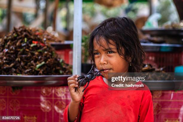 bambina cambogiana che mangia tarantola fritta, mercato di strada, cambogia - insetto foto e immagini stock